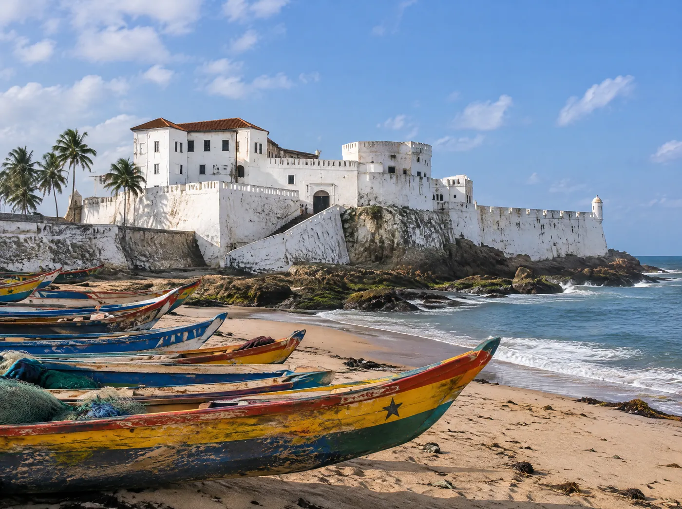 Cape Coast Castle above painted fishing canoes on the beach
